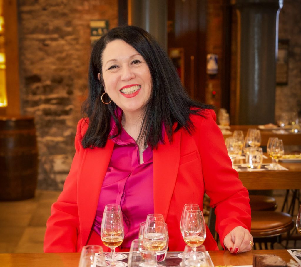MarieAnn, Maisy's granddaughter, smiling at a whiskey tasting table